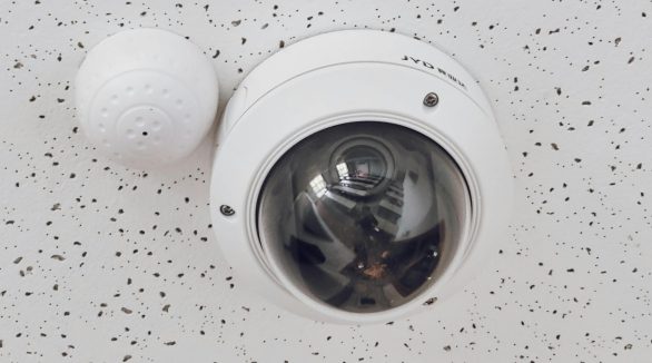 Close-up of a round dome surveillance camera installed on a speckled ceiling for security monitoring.